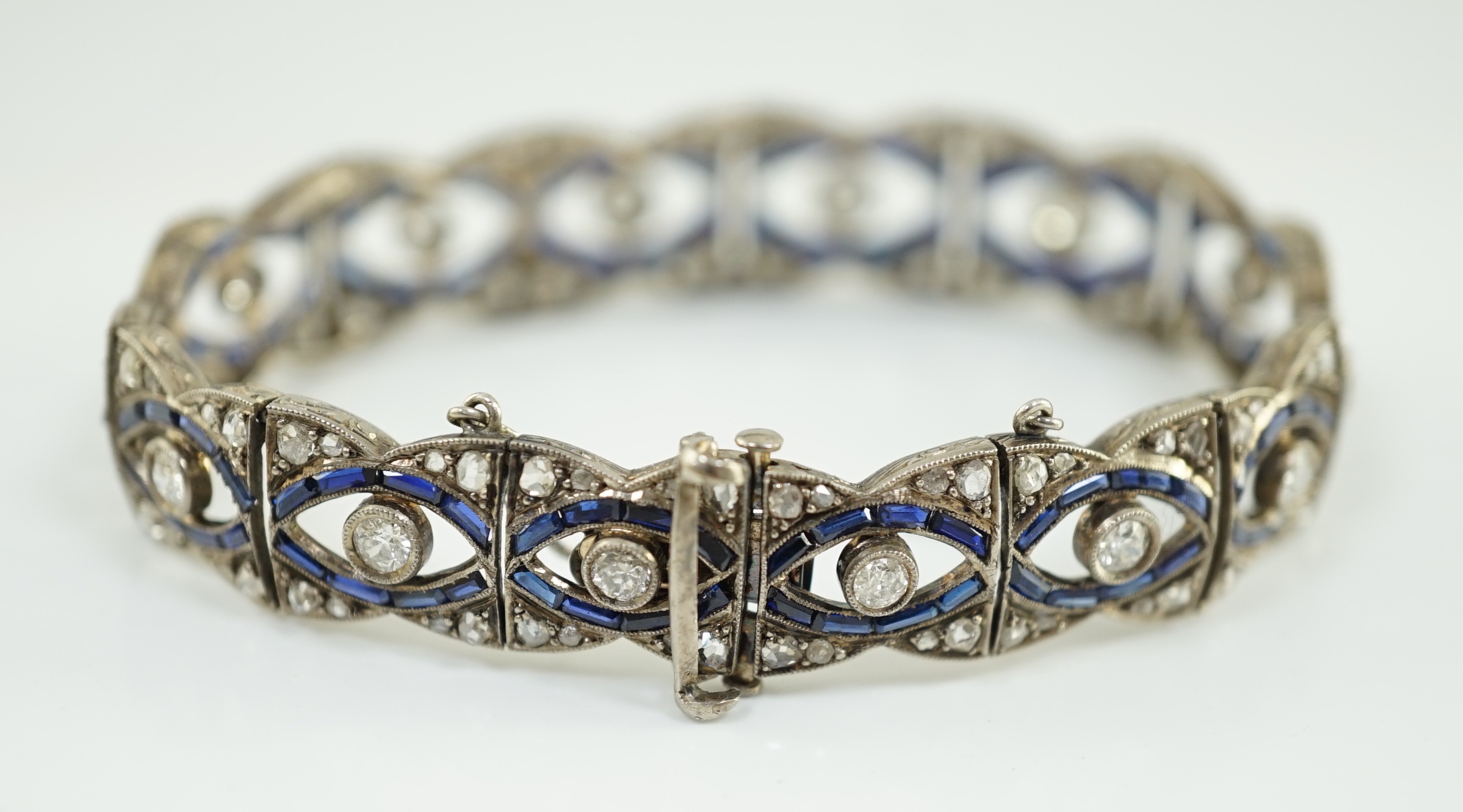 A 1920's 18ct white gold and millegrain set synthetic? sapphire and round and rose cut diamond set bracelet, with safety chain